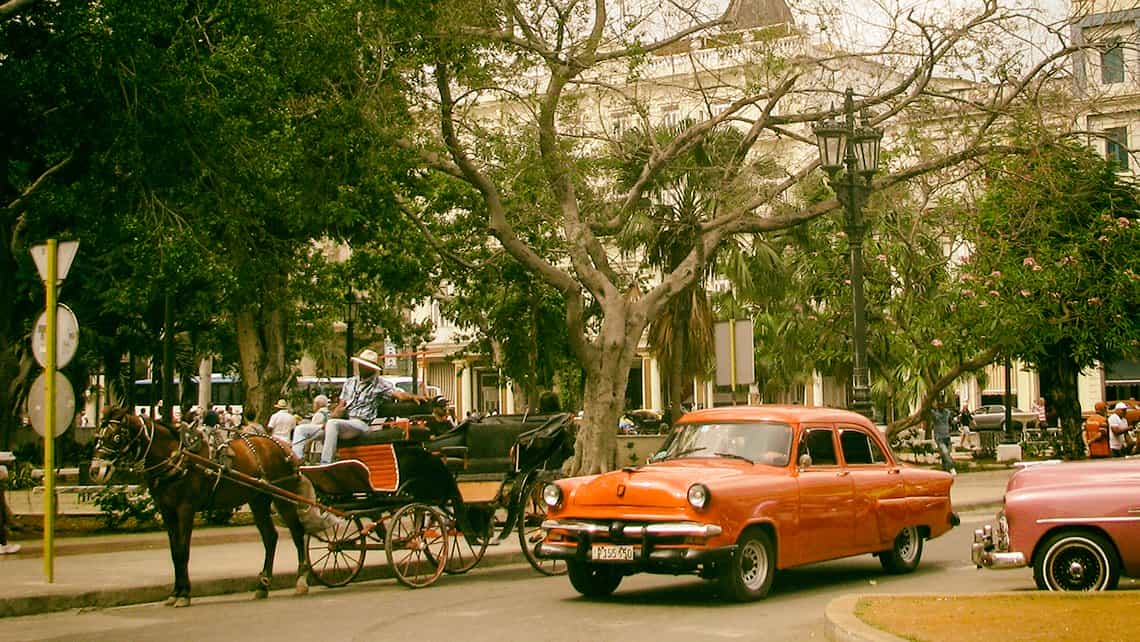 Coches americanos y coches tirados por caballos en el Parque Central, muy cerca de Prado y Neptuno