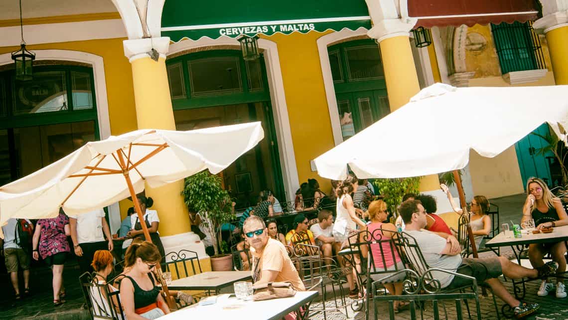 Personas disfrutan de una cerveza en la Plaza Vieja a la sombra de sombrillas