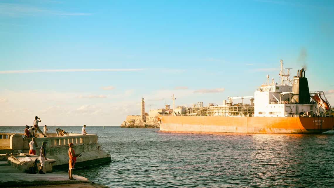 Barco mercante cruza la Bahia de La Habana, al fondo el Faro del Morro