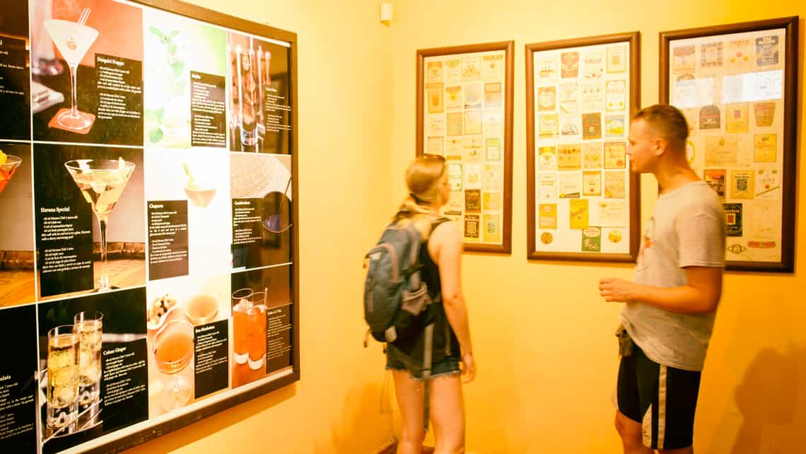 Turistas examinan antiguas etiquetas y recetas de cocteles en el Museo del Ron Havana Club