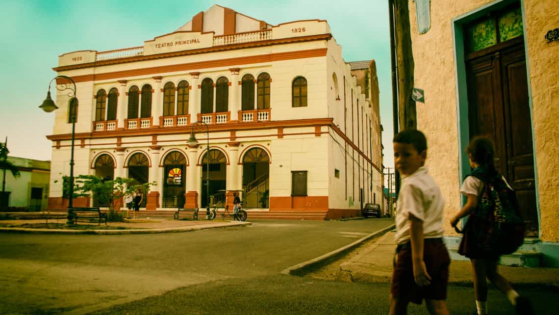 Niños se dirigen a la escuela por las calles de Camaguey, al fondo el Teatro Principal de esta ciudad