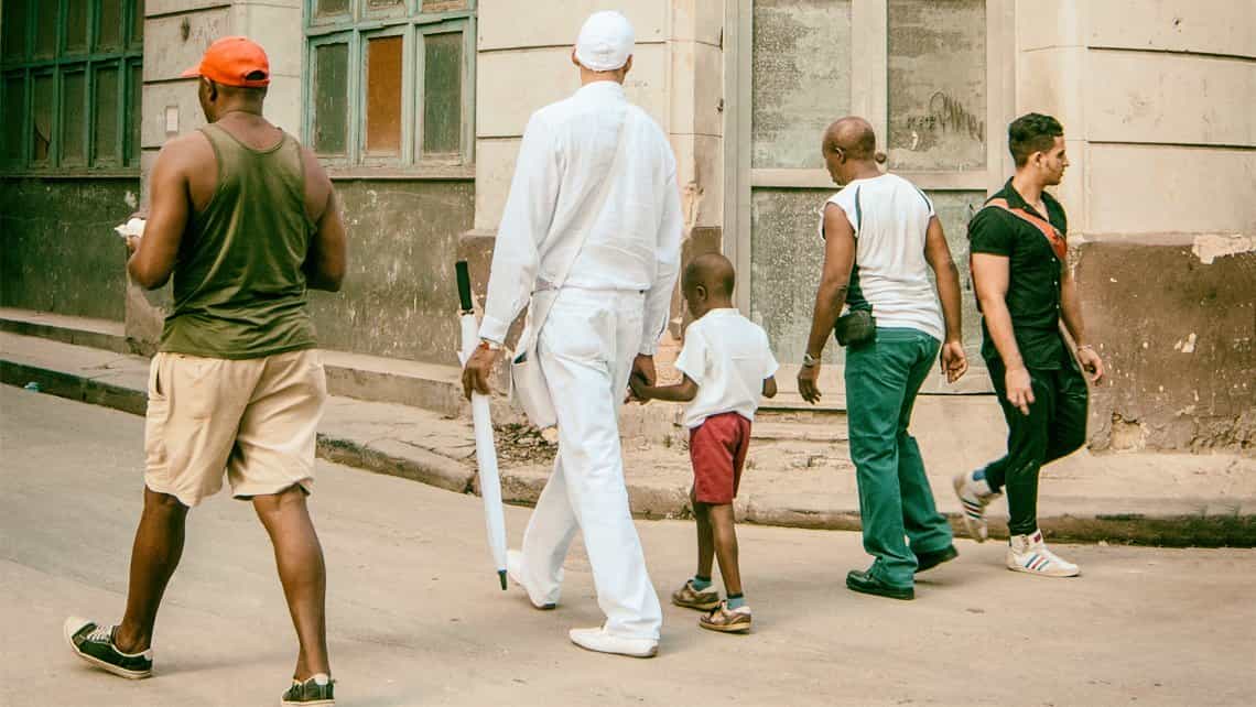Santero camina por las calles de La Habana de la mano de un niño