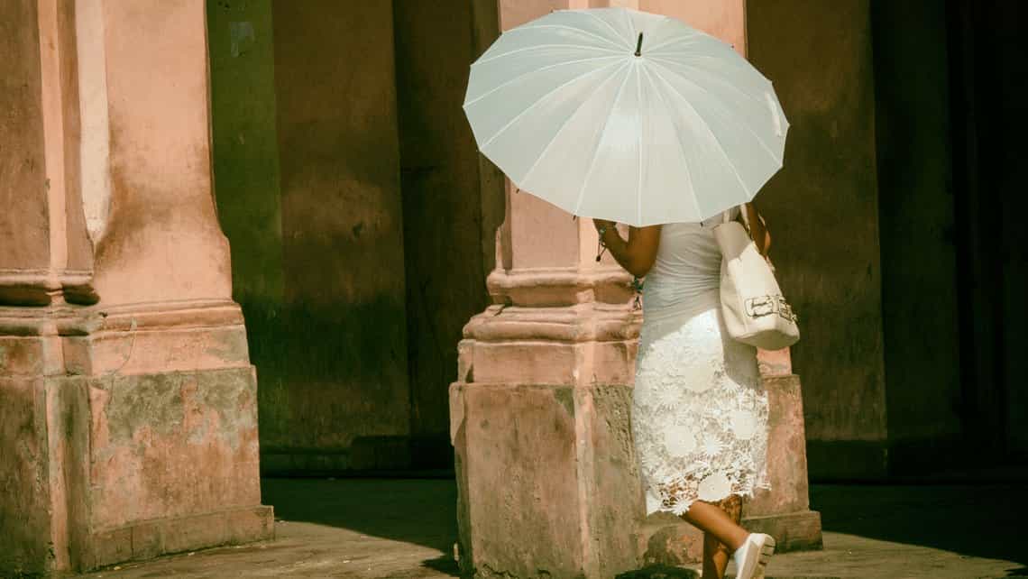 Mujer, vestida toda de blanco, camina por las calles de Centro Habana