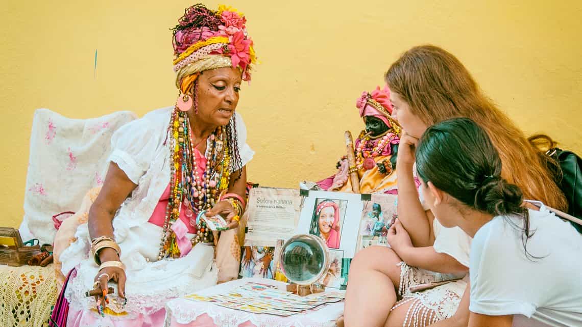 Santera consulta el futuro para dos turistas en la Plaza de Armas de La Habana Vieja