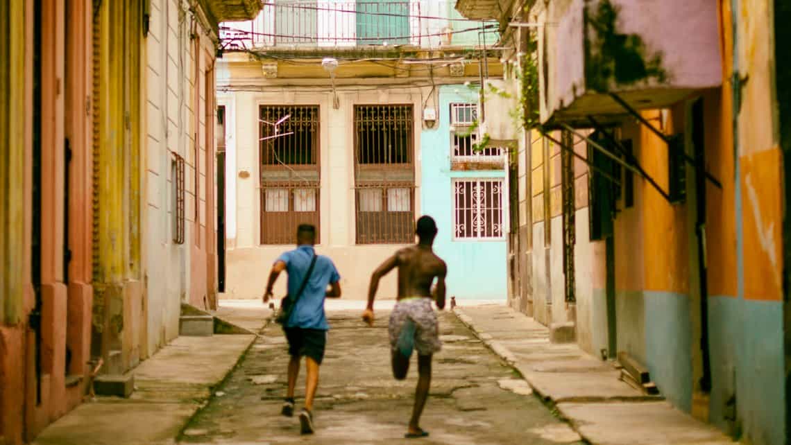 Muchachos corren pos las calles la Habana, a ambos lados solares de Centro Habana