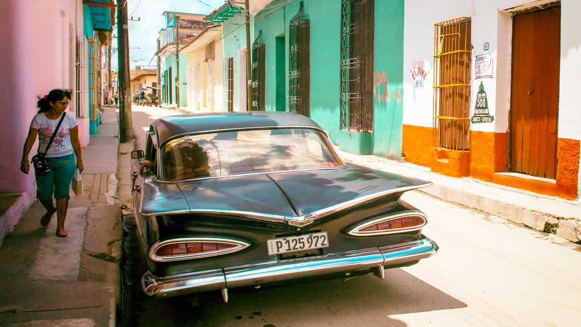Espirituana observa coche antiguo americano de los años 50 en las calles de Sancti Spíritus