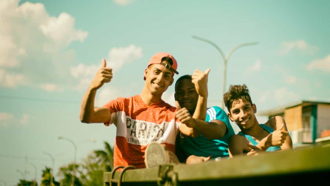 Estudiantes saludan a fotografo cuando viajan por Sagua la Grande a bordo de un camion