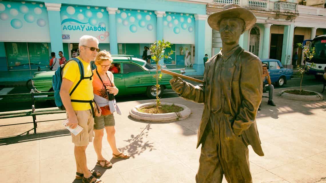 Turistas observan la estatua del famos cantante de musica Cubana Benny More que adorna el Paseo del Prado cienfueguero