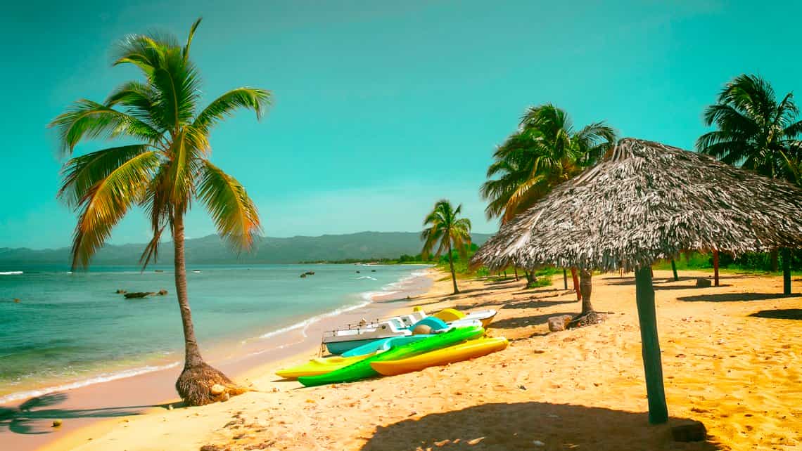 Playa Ancon, cocoteros, sombrillas y kayaks en la orilla del mar Caribe