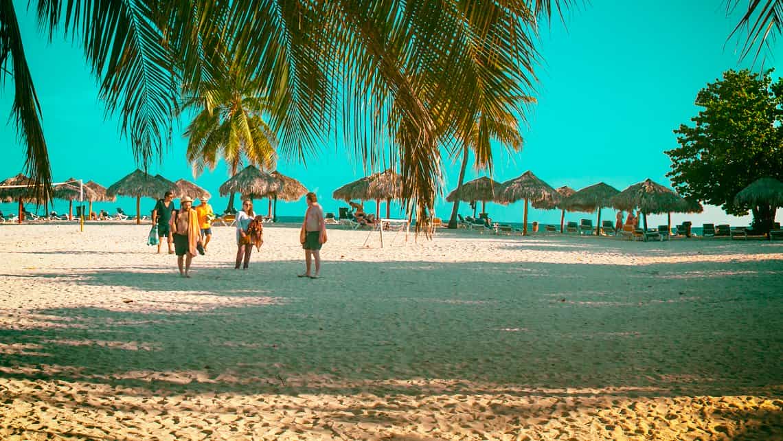 Turistas caminan hacia la orilla del mar Caribe en la Playa Ancon