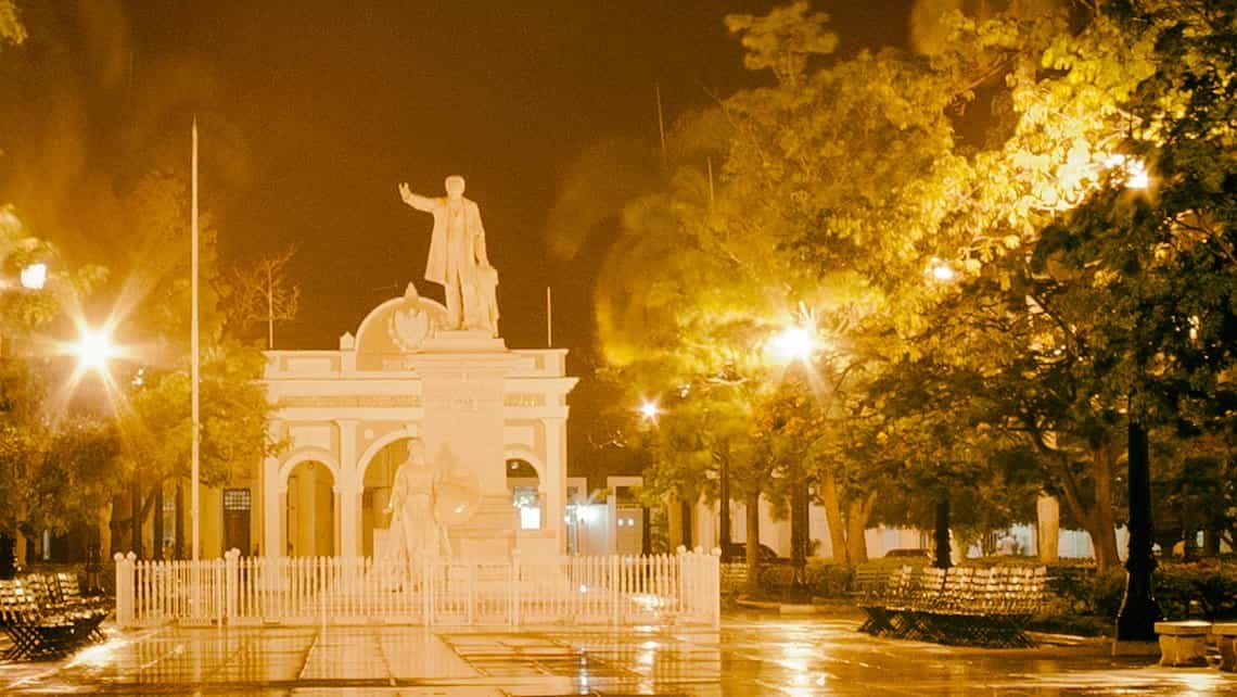 Estatua de Jose Mrati en el parque del mismo nombre en la ciudad de Cienfuegos, al fondo el Arco de Triunfo