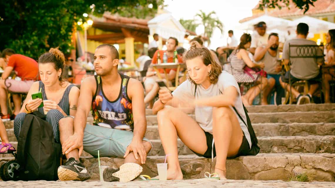 Turistas consultan sus telefonos en la zona Wi-Fi de la Casa de la Musica de Trinidad