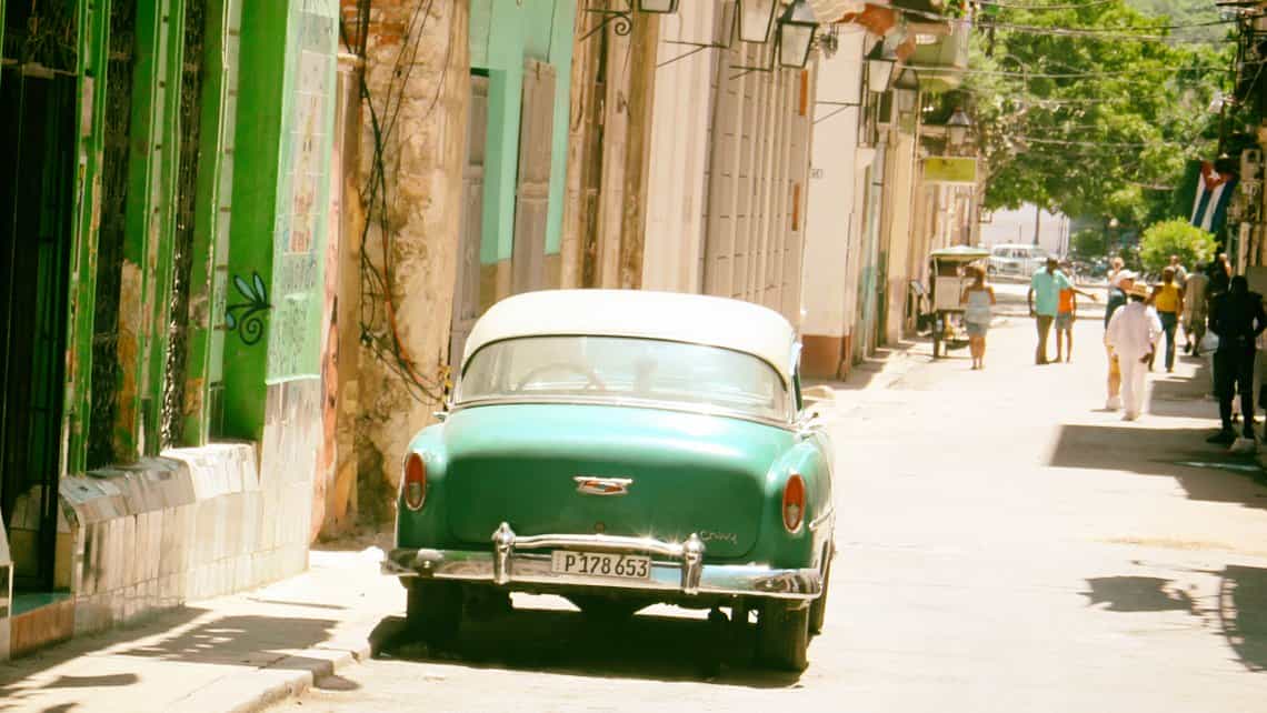 Antiguo Chevrolet aparcado en las calles de La Habana Vieja, al fondo la bandera cubana