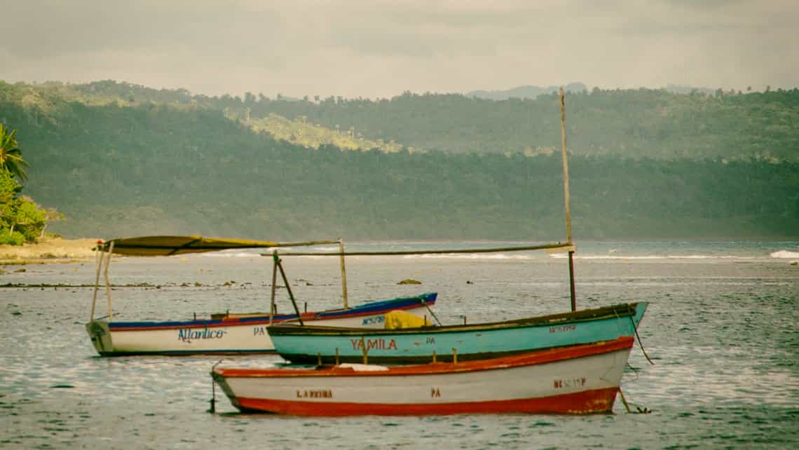 Rusticos botes de pescadores se mecen en las tranquilas aguas de la Bahia de Baracoa
