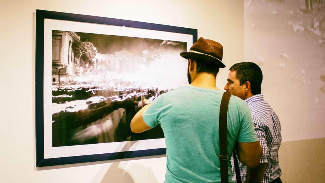 Habaneros observan y comentan fotografias en exhibicion en galeria de arte de La Habana