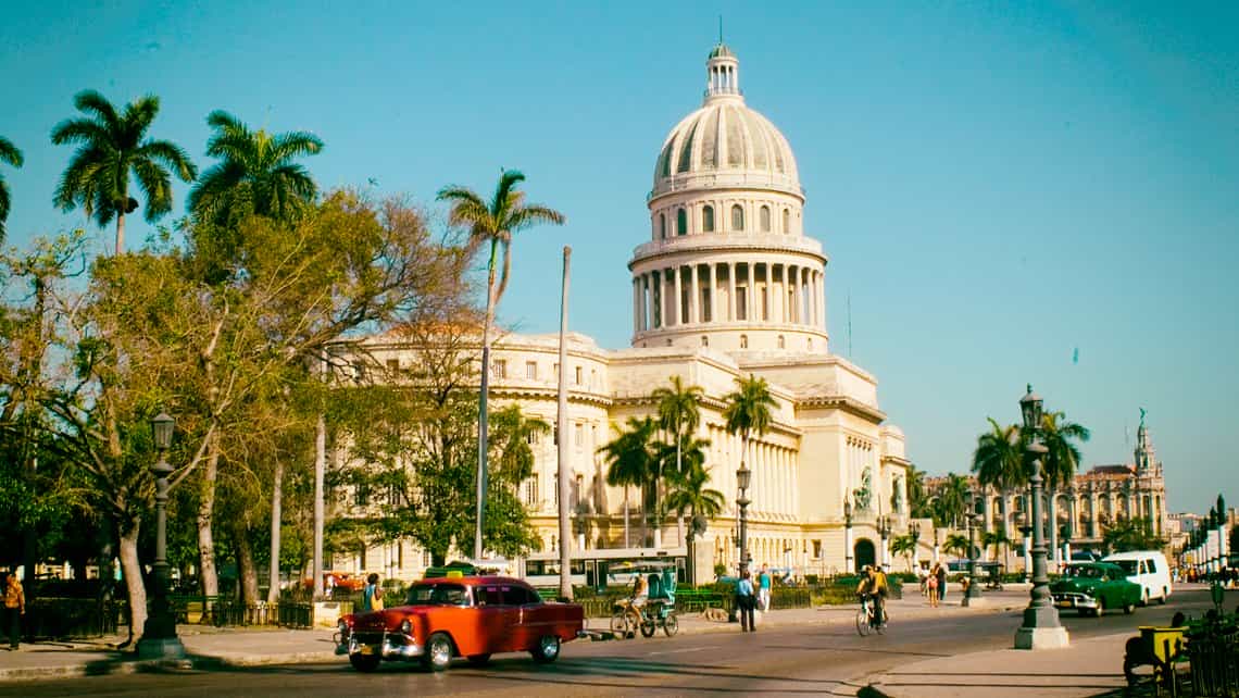 Coches antiguos americanos de los años 50 circulan por las calles de La Habana Vieja, al fondo el Capitolio Nacional
