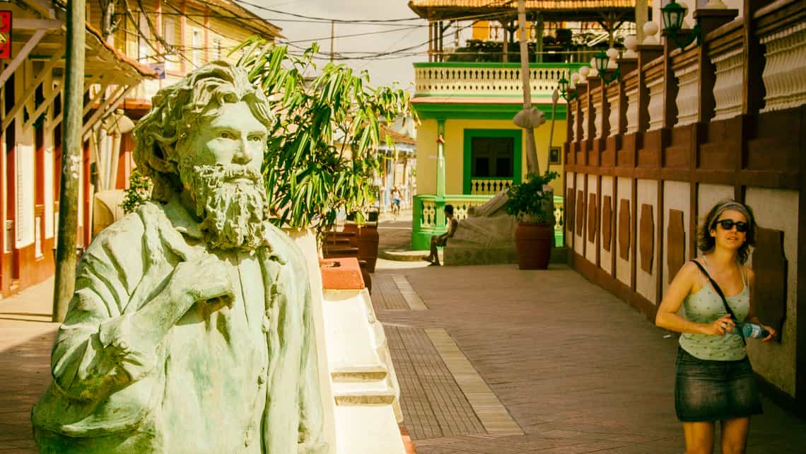 Turista observa estatua en el centro historico de Baracoa