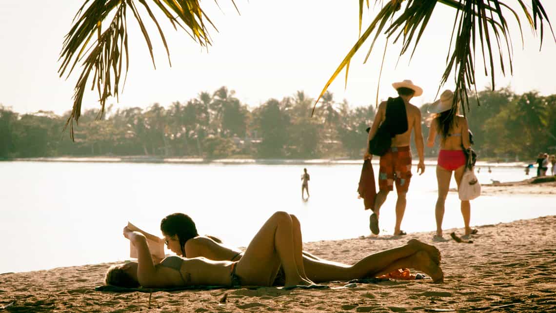 Turistas descansan y pasean por la orilla de Playa Larga