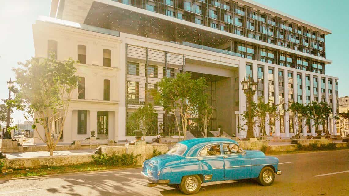 Coche americano antiguo de los años 50 circula por el Paseo del Prado, al fondo el hotel Iberostar Grand Packard