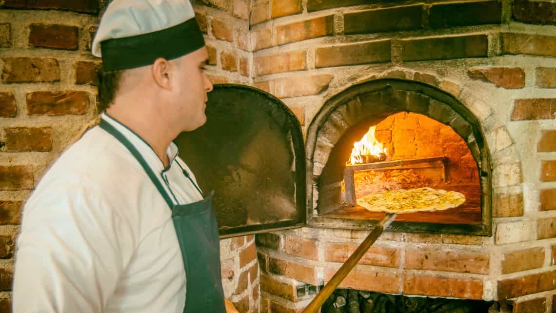 Chef prepara pizza en el horno de leña de la paladar habanera Cinco Esquinas Trattoria
