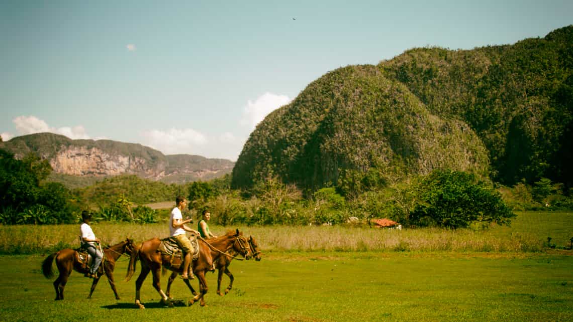 Turistas y guiia recorren el Valle de Viñales a caballo