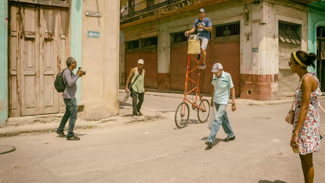 Fotografo trata de acpturar la estampa de un ciclista en bicicleta gigante por las calles de La Habana Vieja