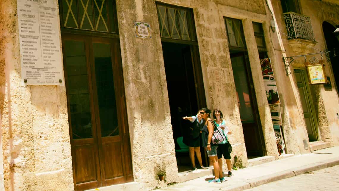 Habanera indica a turistas el camino a la Plaza Vieja por la calle Mercaderes