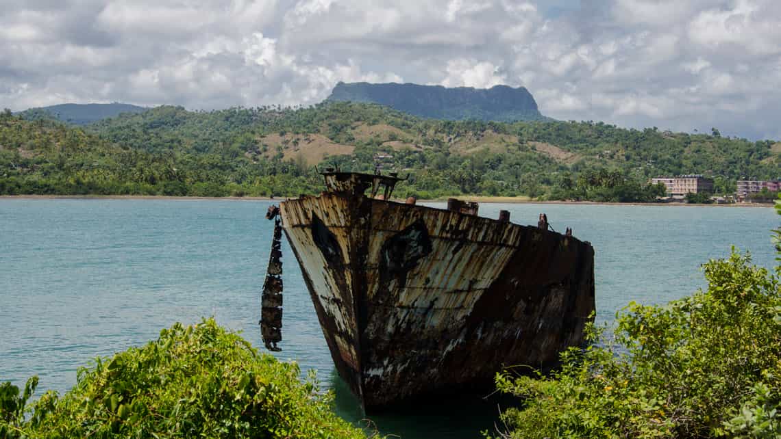 Antigua embarcacion semi-hundida en la costa, al fondo el Yunque de Baracoa