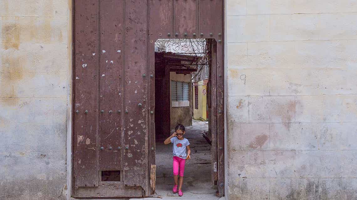 Nina sale a la calle Tejadillo por el antiguo porton de casa solariega de La Habana Vieja