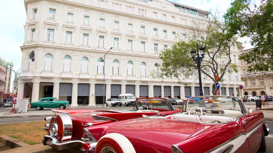Coches americanos de los 50, almendrones, parqueados en la acera del Gran Hotel Manzana Kempinski La Habana