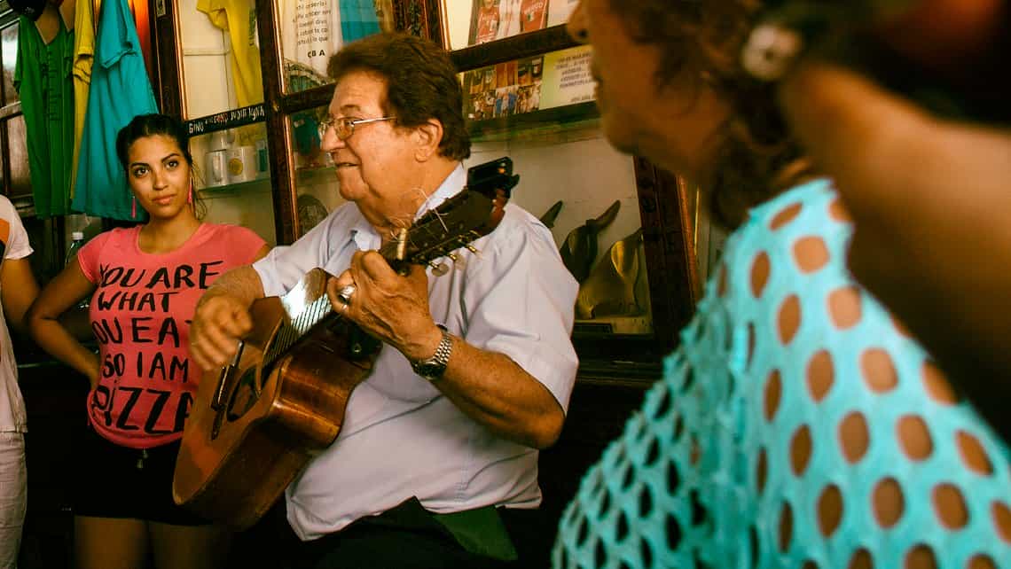 Musico cubano toca la guitarra para una audiencia de cubanos y viajeros foraneos