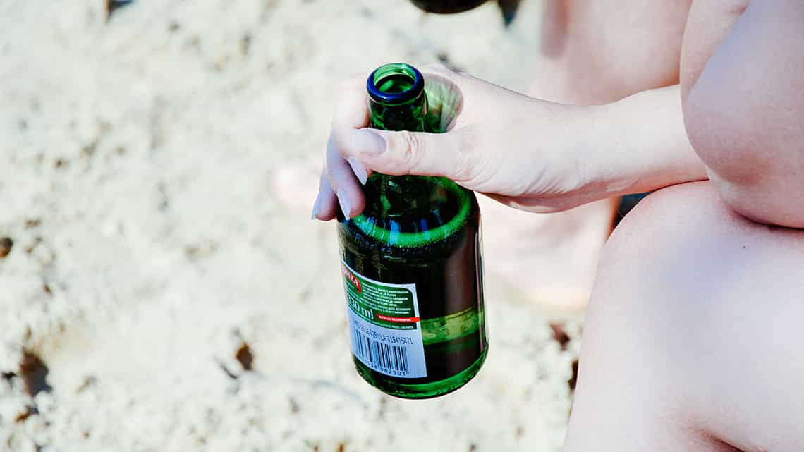 Chica bebe cerveza en las arenas de la playa de Varadero