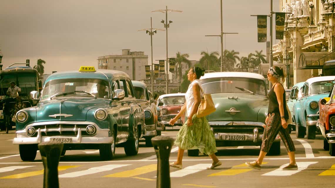 Mujeres cruzan una avenida frente el Parque Central de La Habana