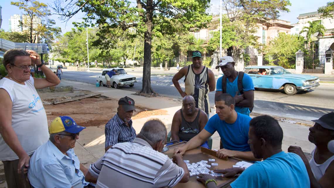 Un grupo de locales juega domino en un espacio adyacente a la calle Linea