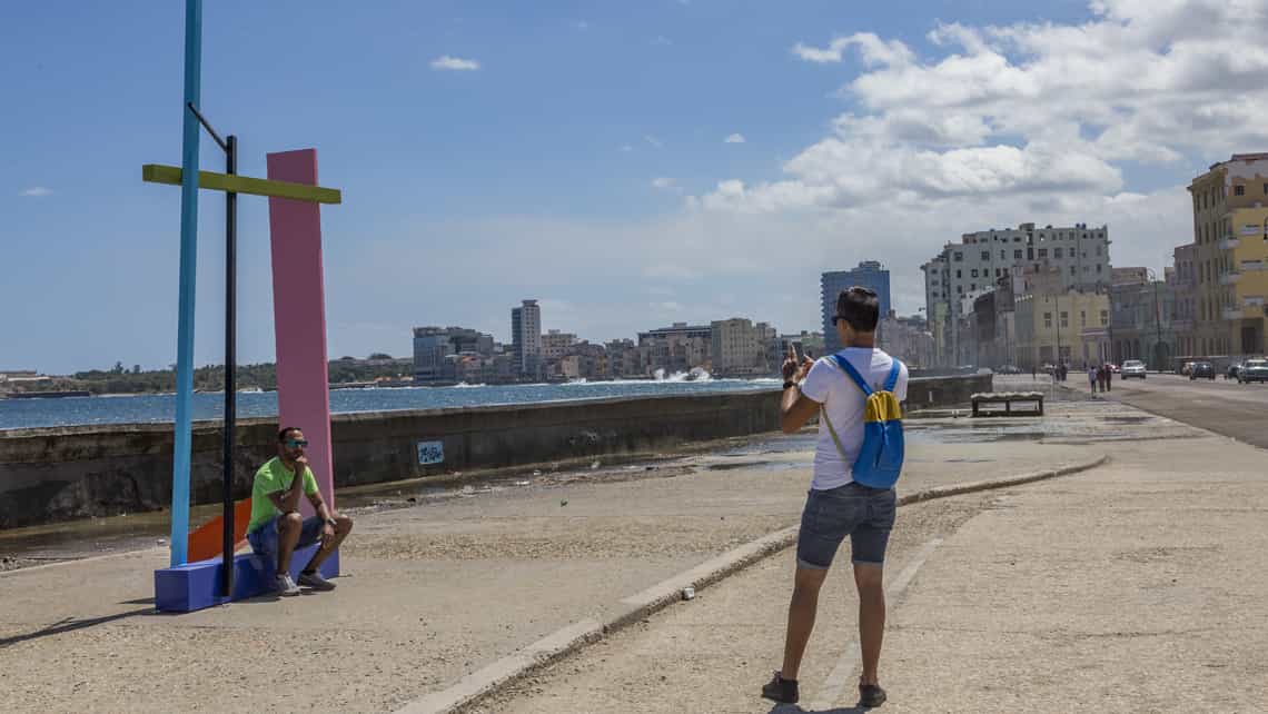 Viandantes haciendose fotos en obras de la Bienal emplazadas en el Malecon habanero