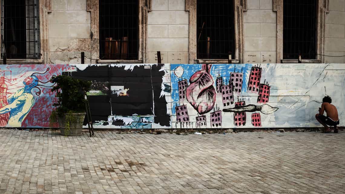 Muchacho utiliza el muro de un espacio publico de La Habana para pintar graffitis