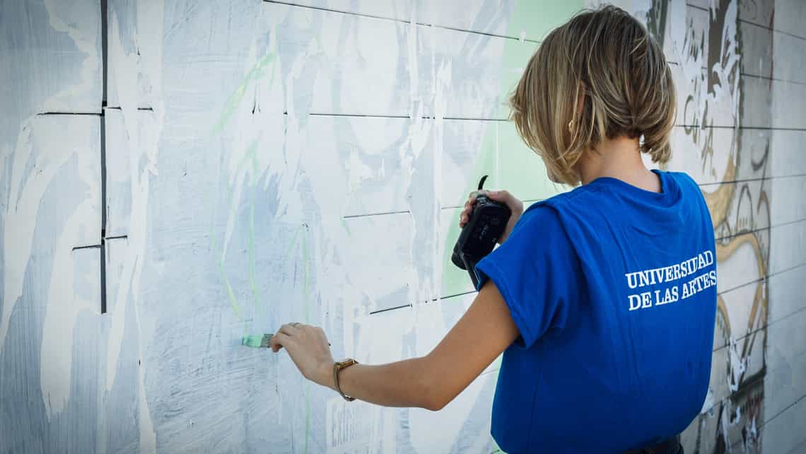 Estudiante de la Universidad de las artes pinta un muro de un espacio publico