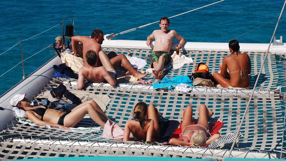 Turistas disfrutan y toman el sol a bordo del catamaran
