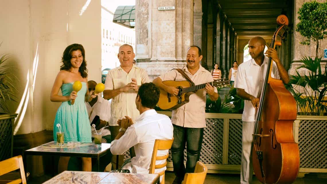 Turista conversa con un grupo musical en el Cafe de la Acera del Louvre