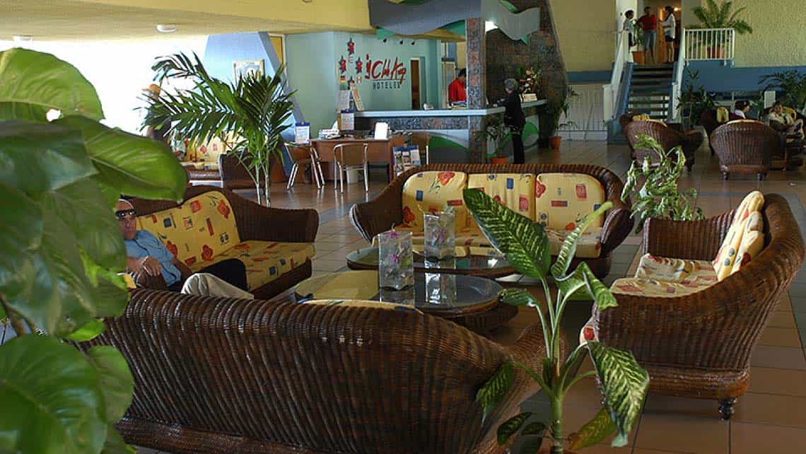 Plantas tropicales y muebles de rattan en un espacio interior del Hotel Rancho Luna