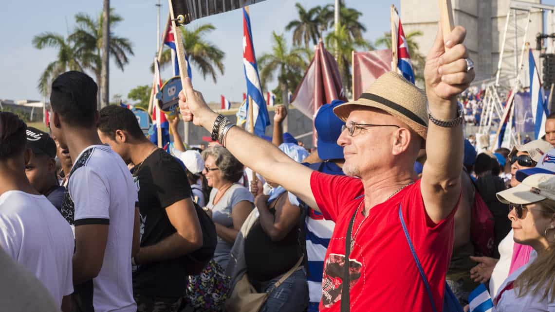 Grupo de personas ondean banderas cubanas en la plaza de la Revolución