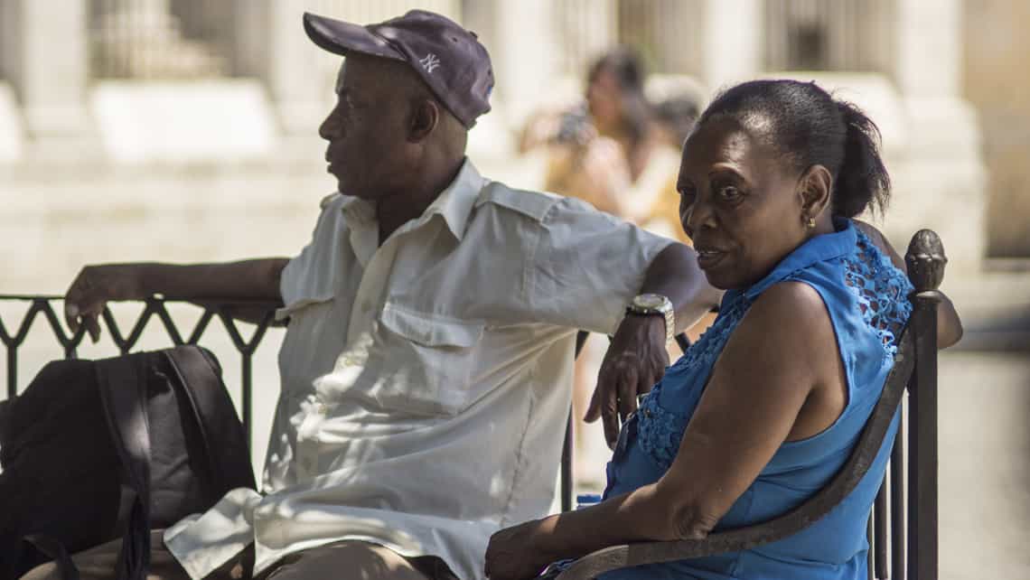 Dos personas sentadas en un banco de La Habana
