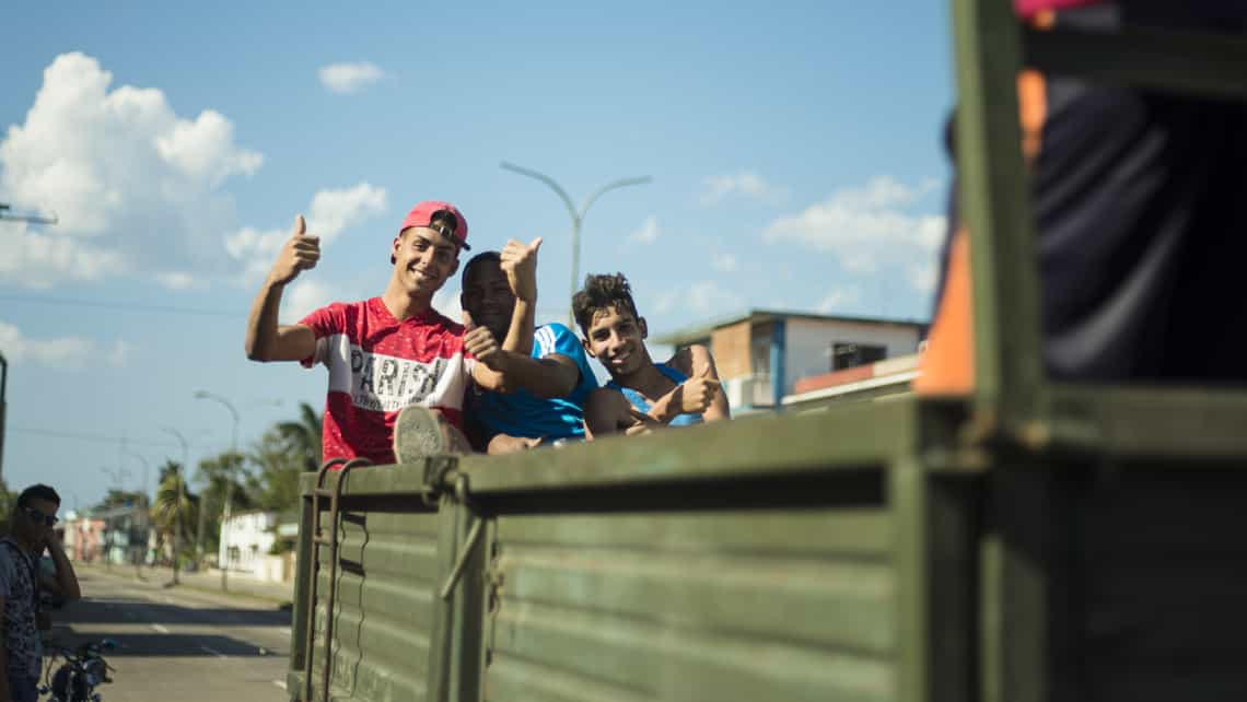 Jóvenes cubanos saludan desde un camión 