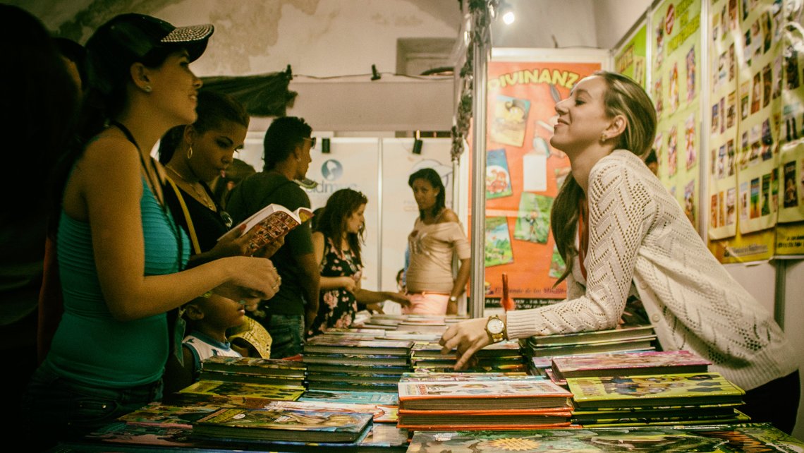 Participantes en la Feria del Libro de La Habana conversan con una de las vendedora