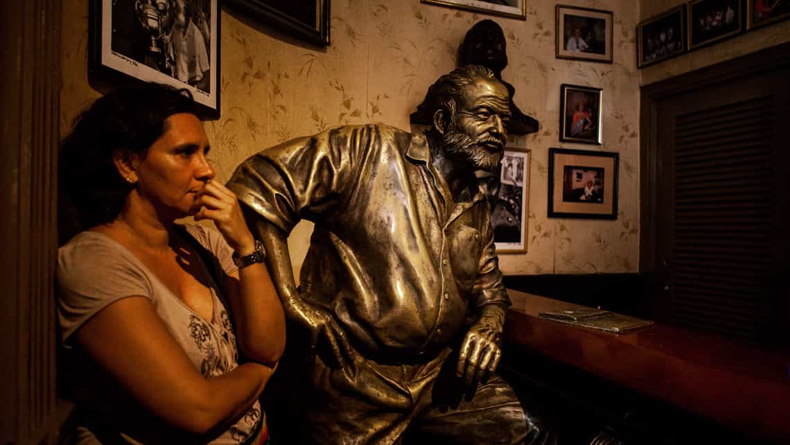 Viajera posando para foto junto a la estatua de Ernest Hemingway en El Floridita de La Habana