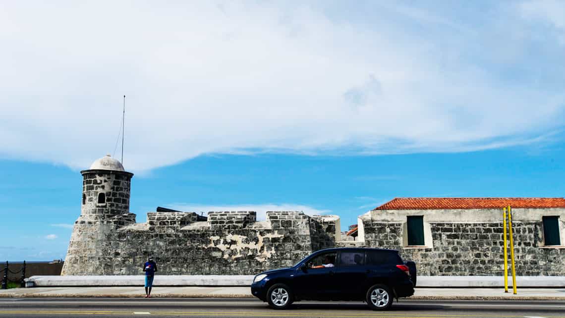 Auto recorriendo el Malecon frente al Castillo de la Punta, Habana, Cuba