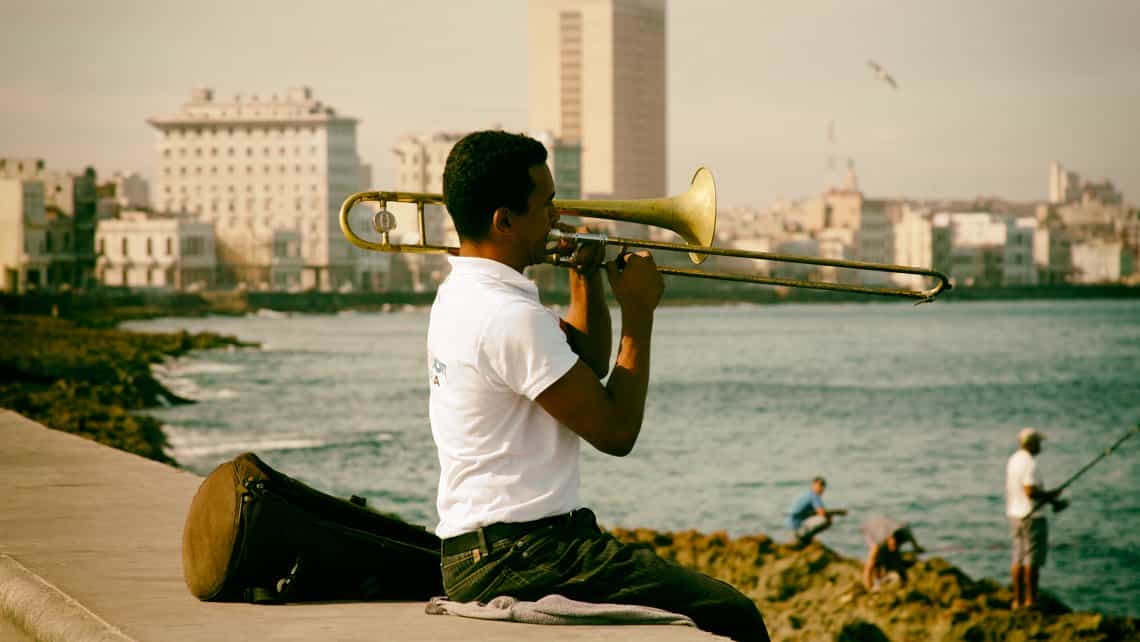 Musico practica en el Malecon, al fondo unpescador prueba suerte