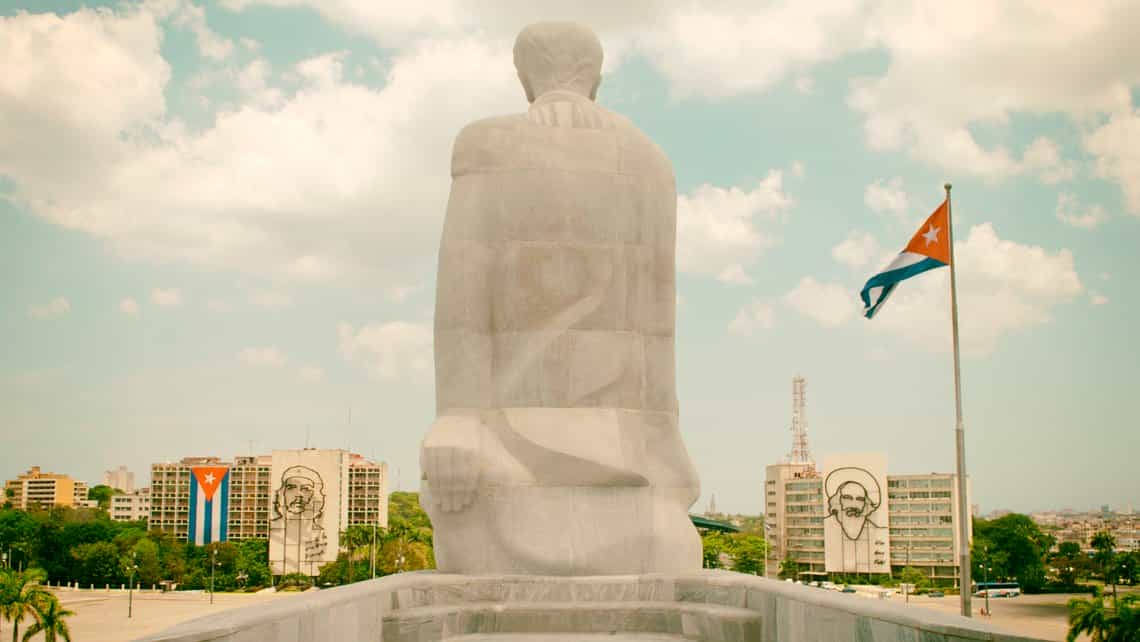 Estatua de Marti en la Plaza de la Revolucion, al fondo banderas cubanas y las esculturas del Che y Camilo