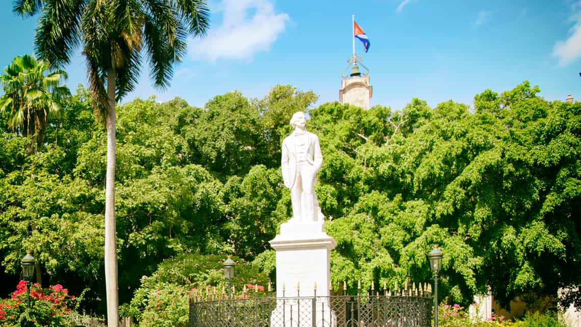 Estatua de Carlos Manuel de Cespedes en la Plaza de Armas, al fondo la bandera cubana
