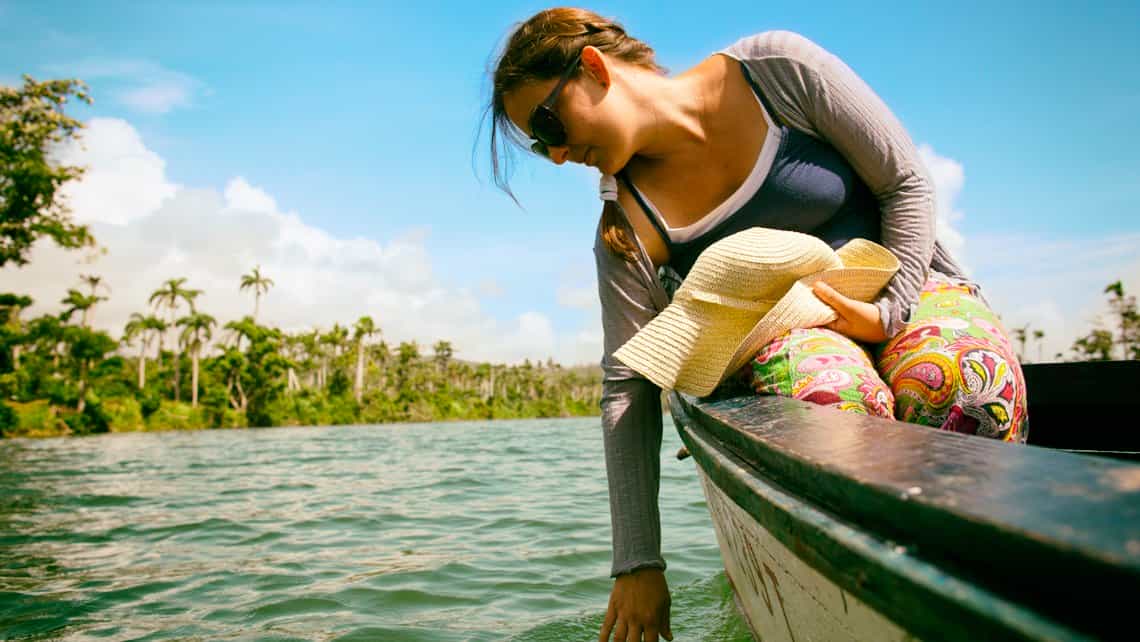 Turistas prueba el agua del Rio Cauto durante un paseo en bote